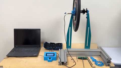The spin-down test stand on the bench, the weighted plate and hub in the frame with the laptop and data logger alongside.
