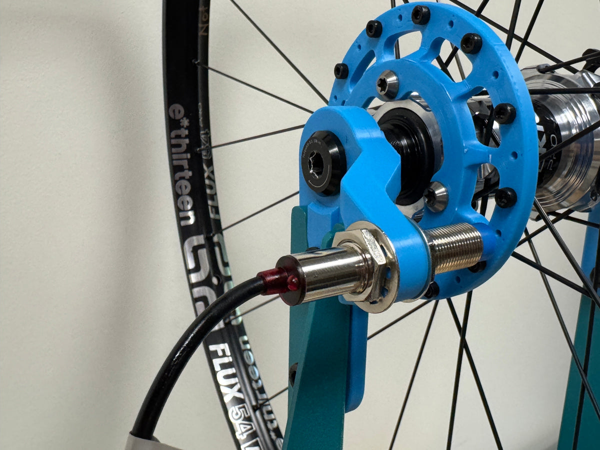 A complete Sidekick wheel on the stand with its freehub held in the blue fixture.