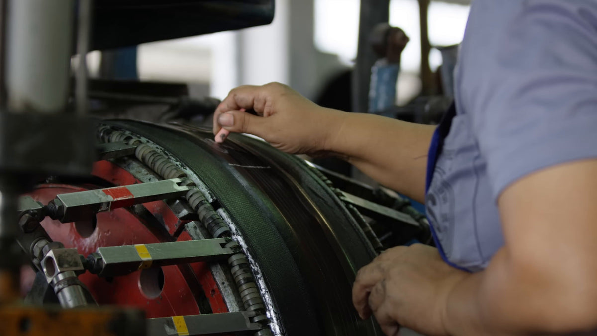 A builder's hands laying a ply onto the tire building drum. Still from Freehub Magazine's film Made With Love.