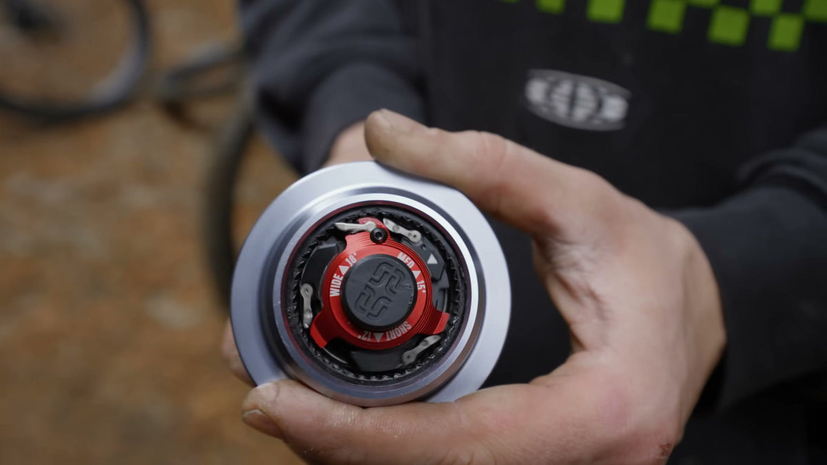 A Sidekick rear hub held in one hand, the red adjuster ring marked SHORT, MED and WIDE.
