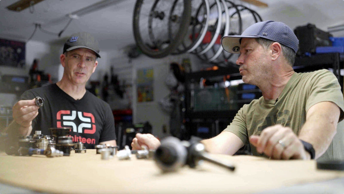 Two e*thirteen engineers talking over Sidekick hub parts at a workbench