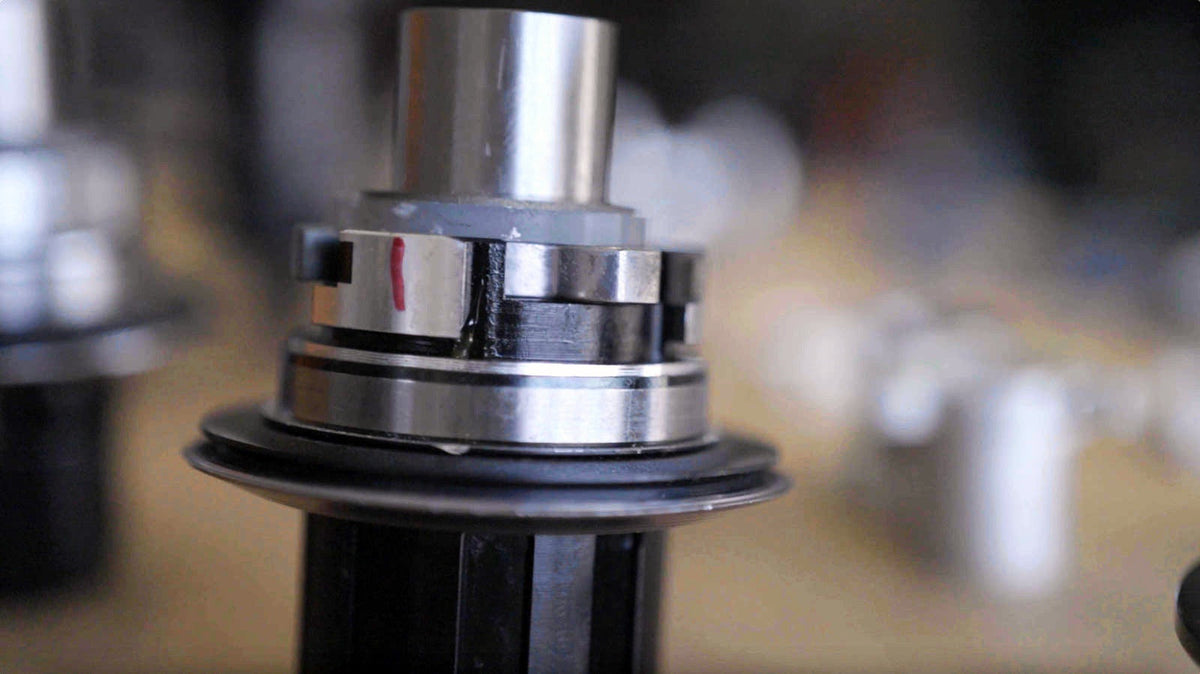 A Sidekick hub shell held in a machine, a red witness mark on the freehub